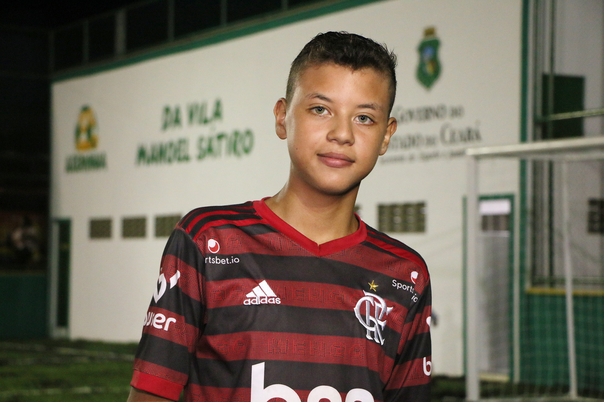 garoto sorrindo para a foto vestido com camisa do Flamengo
